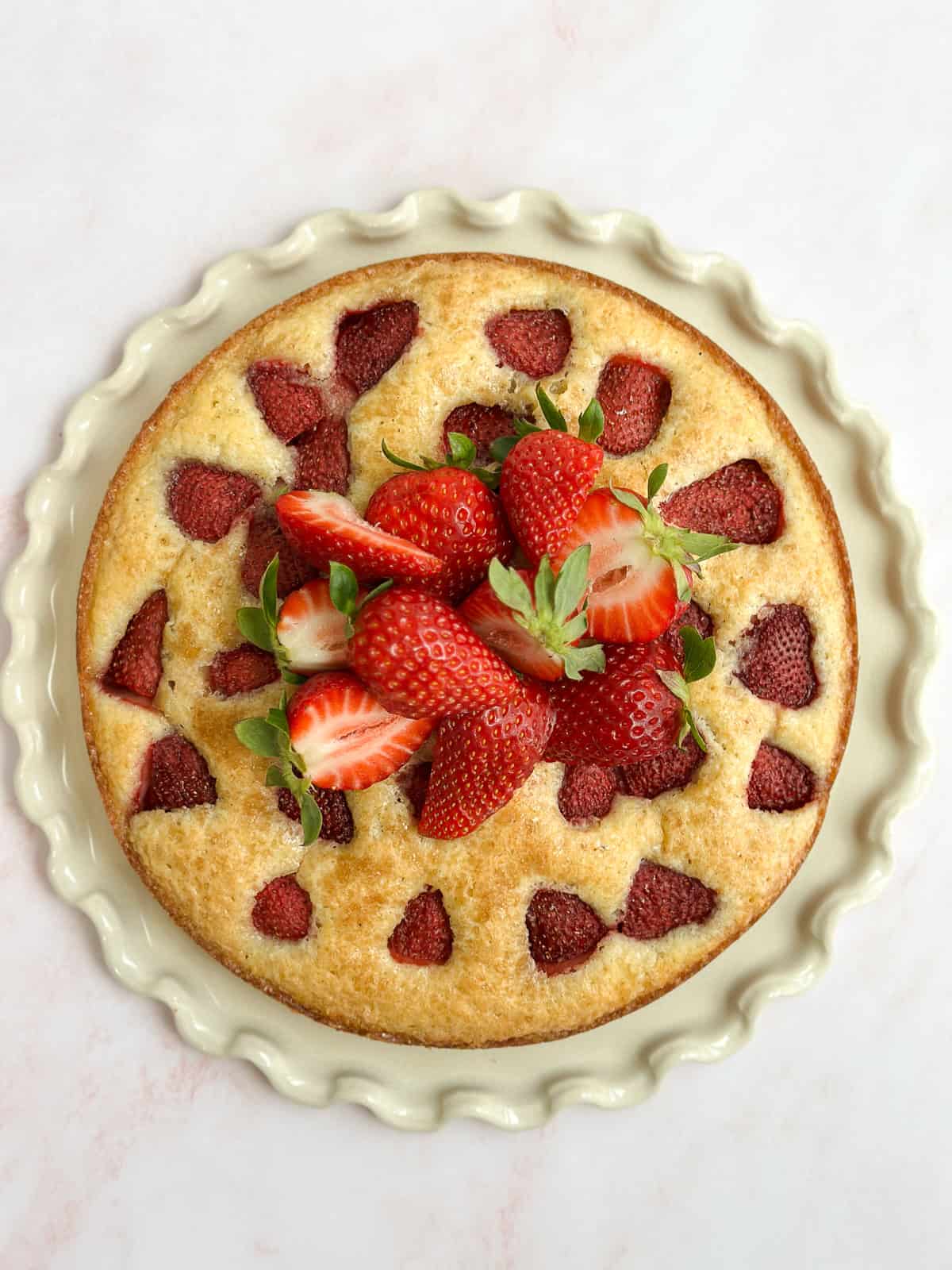 the whole strawberry buttermilk cake topped with fresh strawberries.