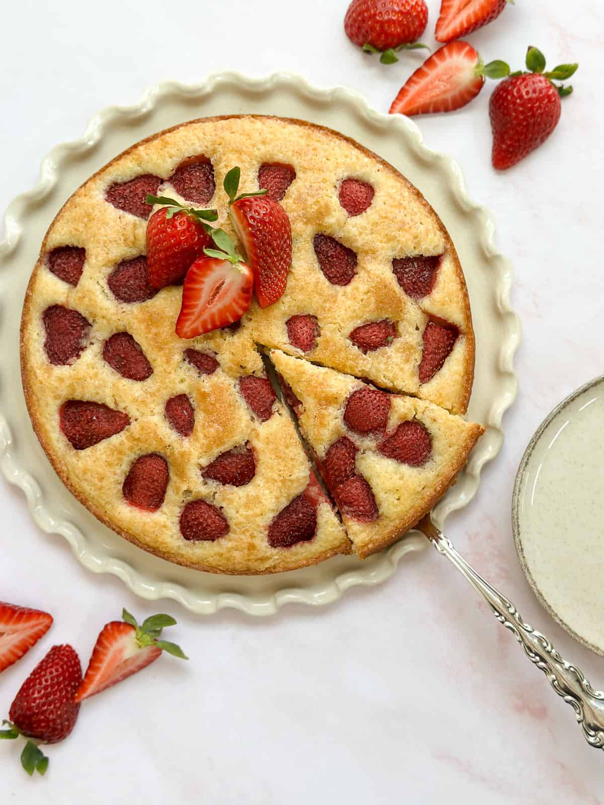 the strawberry buttermilk cake with a slice being taken from it.