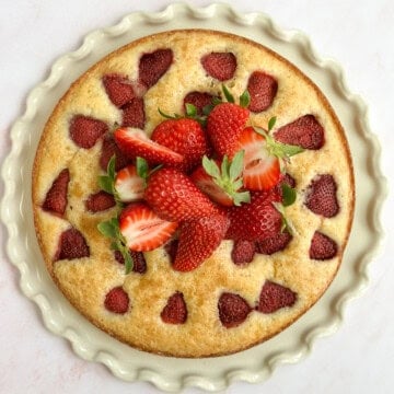 the whole strawberry buttermilk cake topped with fresh strawberries.