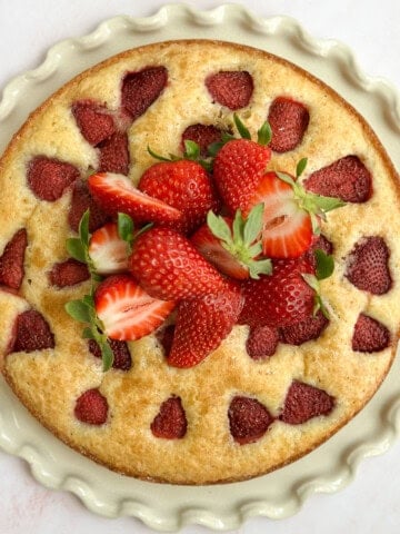 the whole strawberry buttermilk cake topped with fresh strawberries.