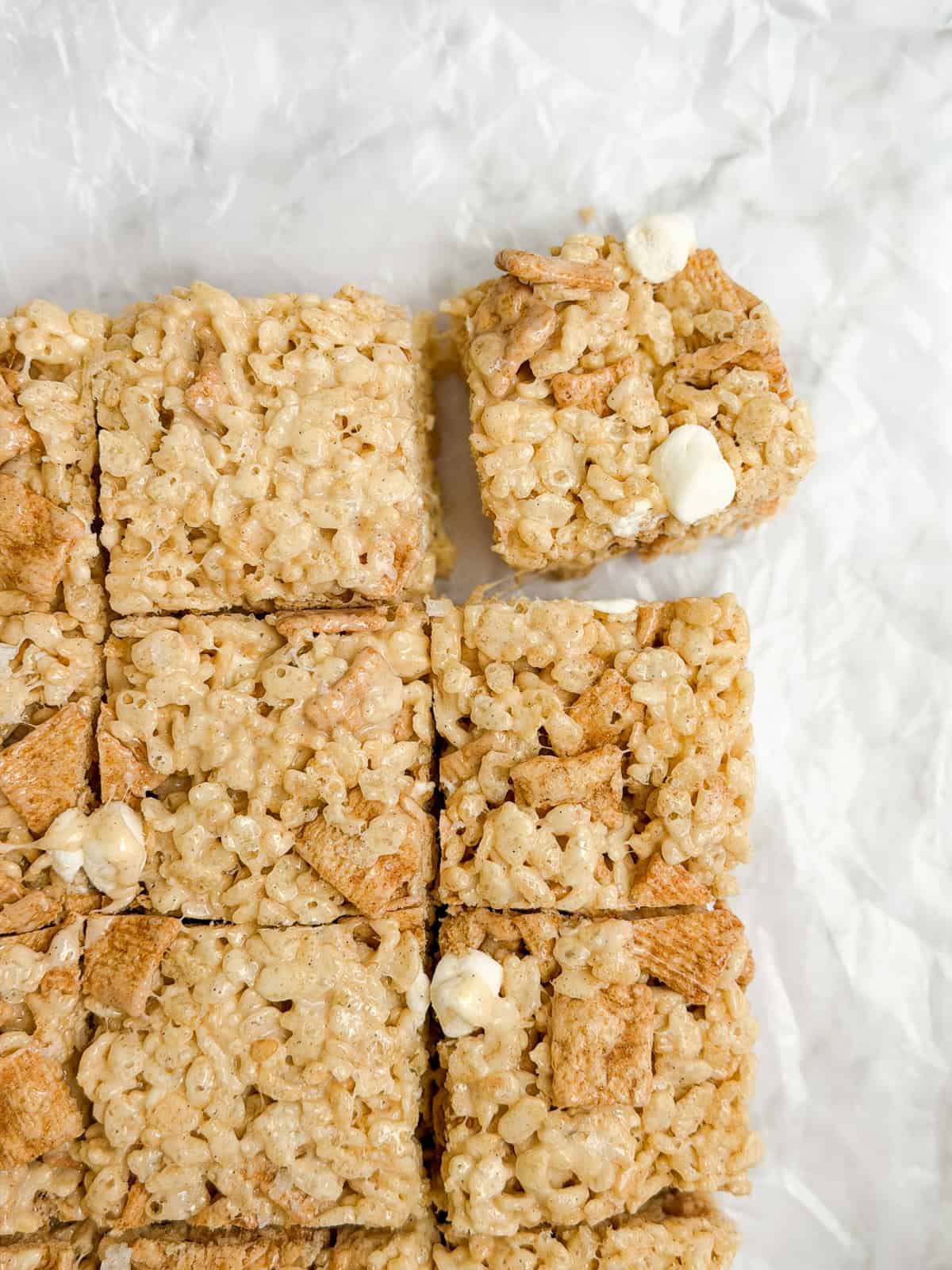 cinnamon toast crunch marshmallow treats cut into squares with one being pulled.