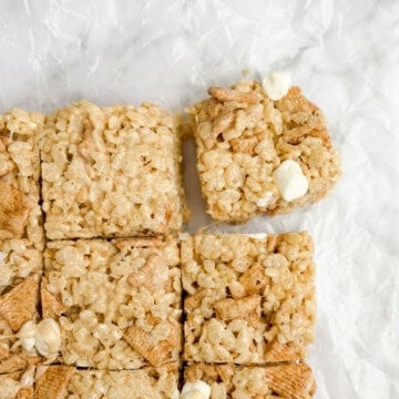cinnamon toast crunch marshmallow treats cut into squares with one being pulled.