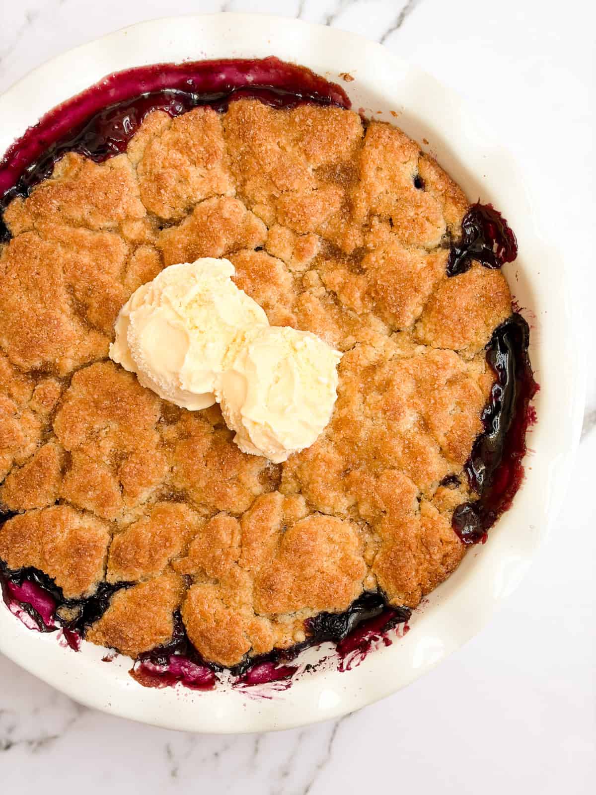 the whole pan of blueberry peach cobbler with scoops of ice cream on top.