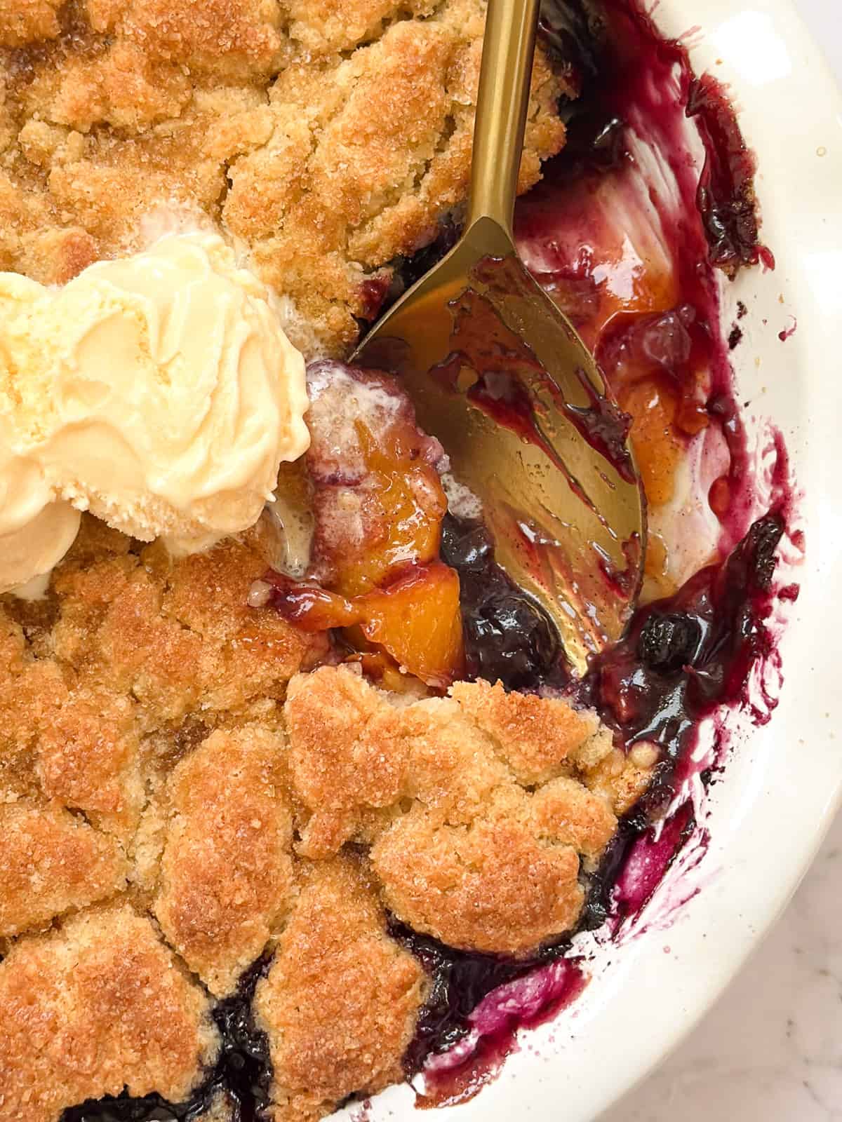 a spoon scooping into the blueberry peach cobbler.