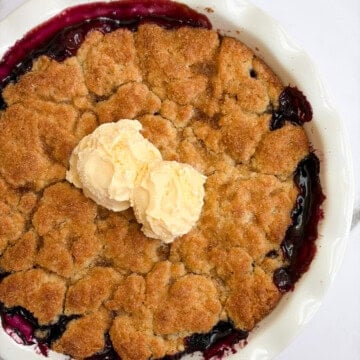 the whole pan of blueberry peach cobbler with scoops of ice cream on top.