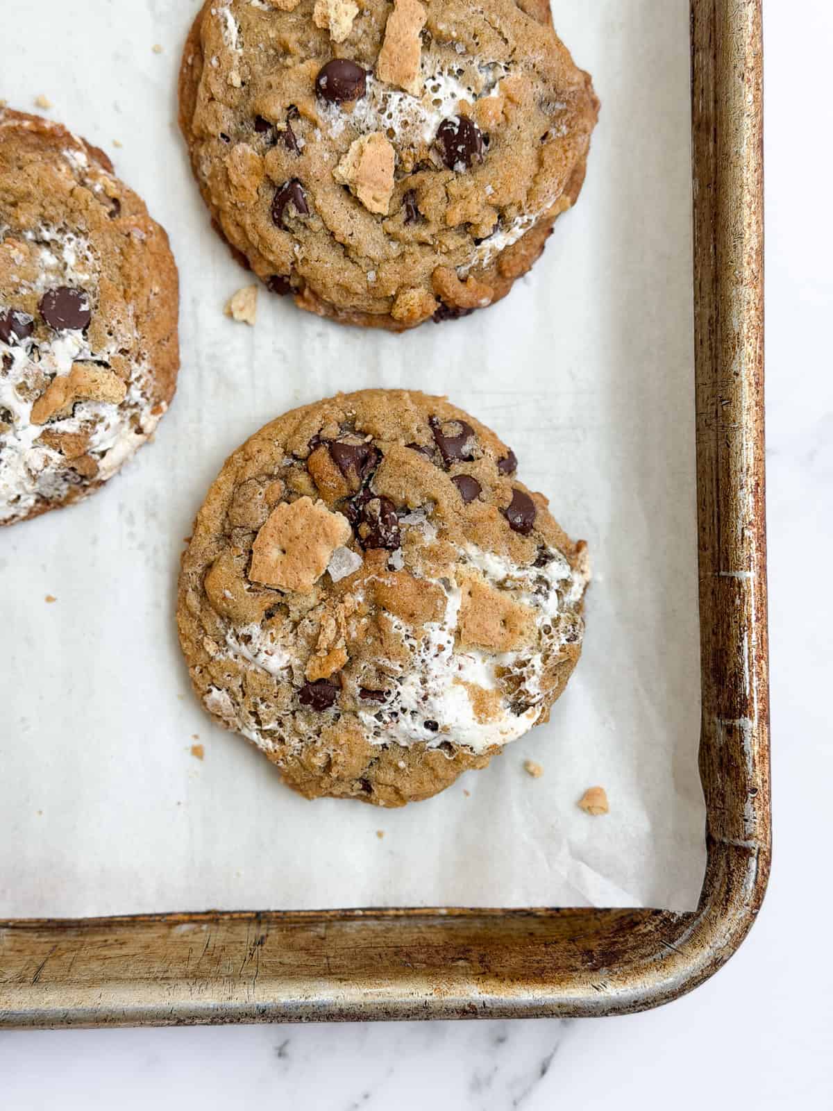 a few of the brown butter s'mores chocolate chip cookies on a baking sheet.