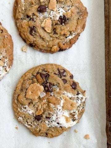 a few of the brown butter s'mores chocolate chip cookies on a baking sheet.