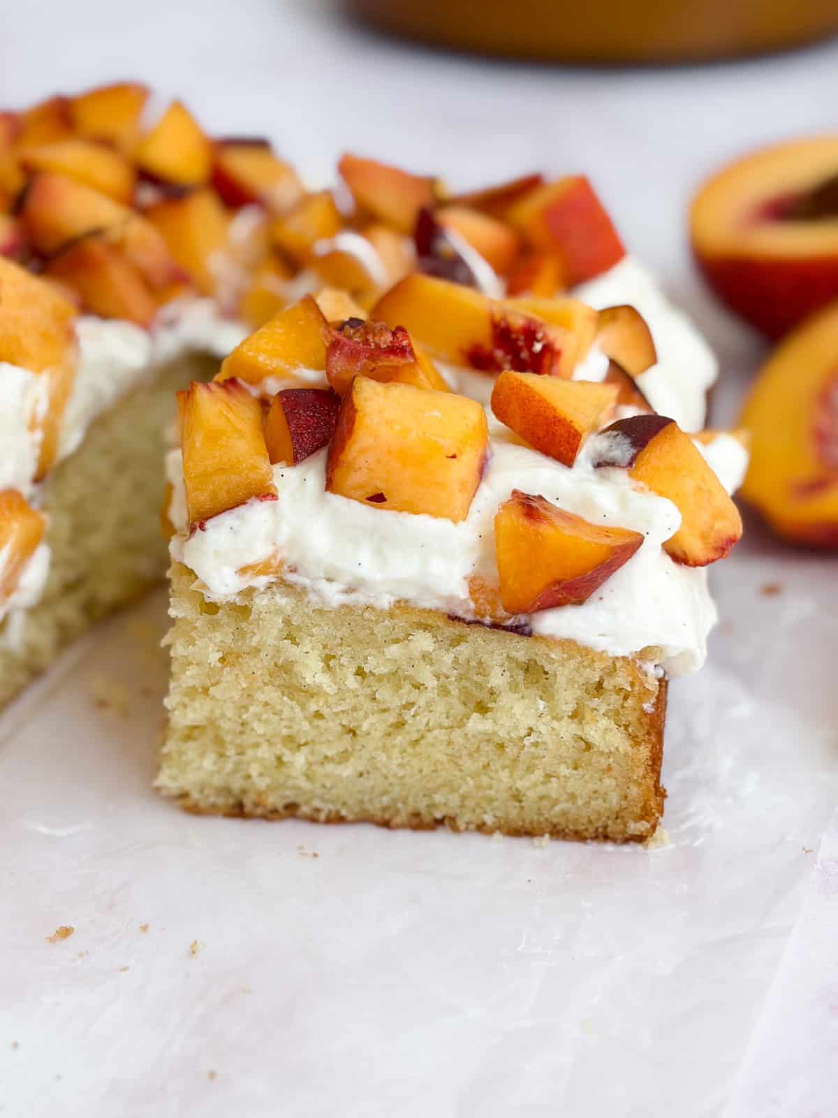a side view of the peaches and cream cake piled high with fresh peaches.