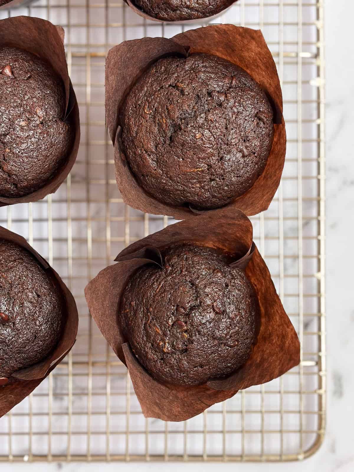 a close up of double chocolate zucchini muffins on a cooling rack.