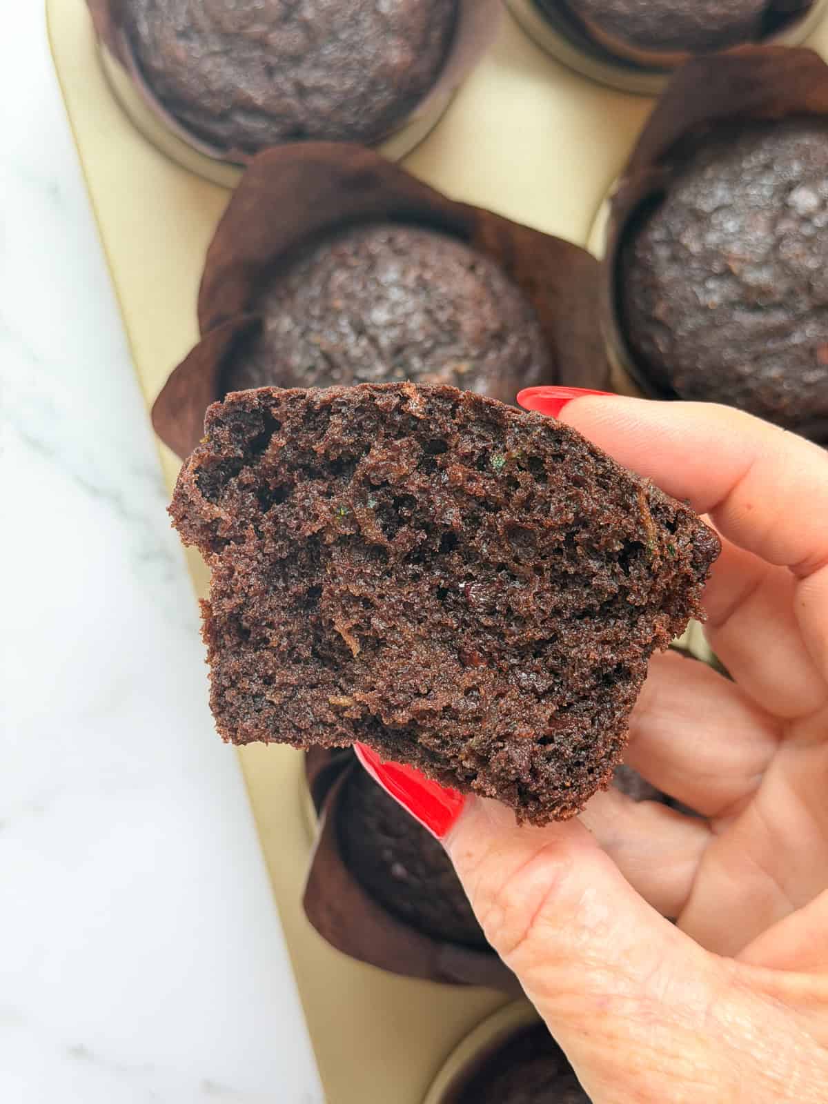 a double chocolate zucchini muffin broken in half so you can see the inside texture.