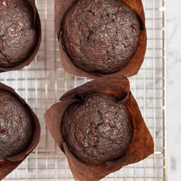 a close up of double chocolate zucchini muffins on a cooling rack.